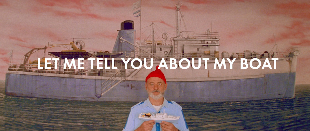 Bill Murray stands holding a model ship, in front of a painting of the same ship, from Wes Anderson’s The Life Aquatic